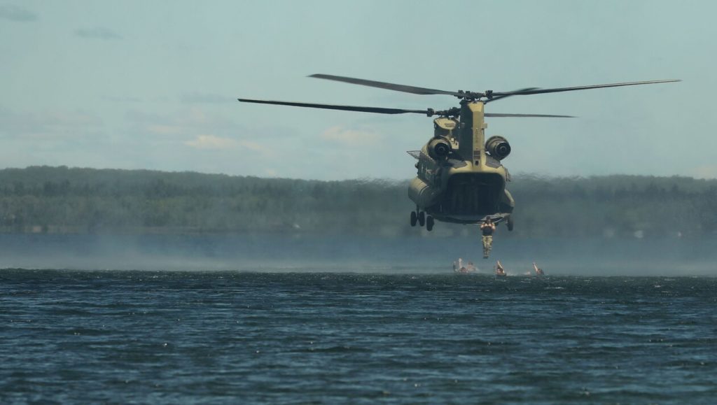 helicopter hovers over water during a training operation at Camp Grayling
