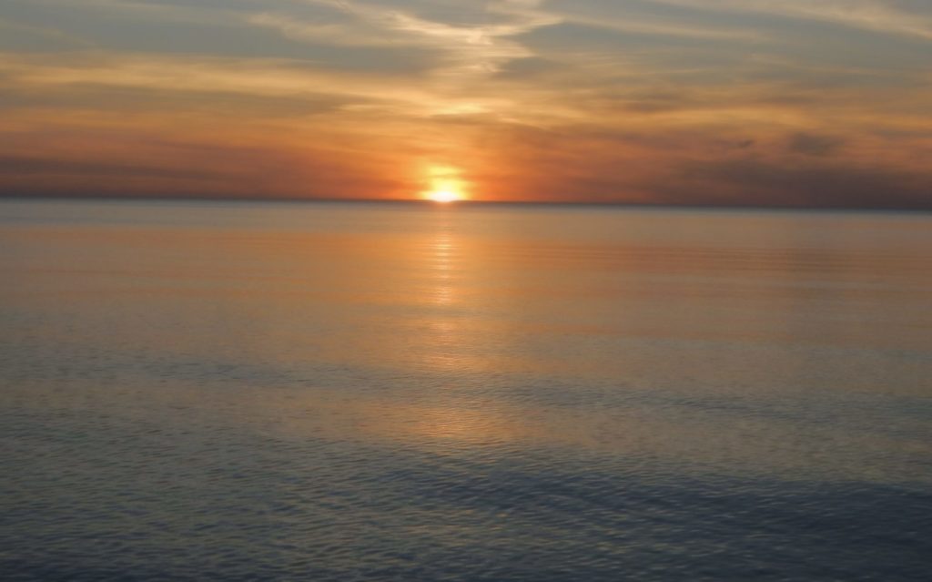 The image shows a sunset over Lake Michigan at Oval Beach, Saugatuck, Michigan.